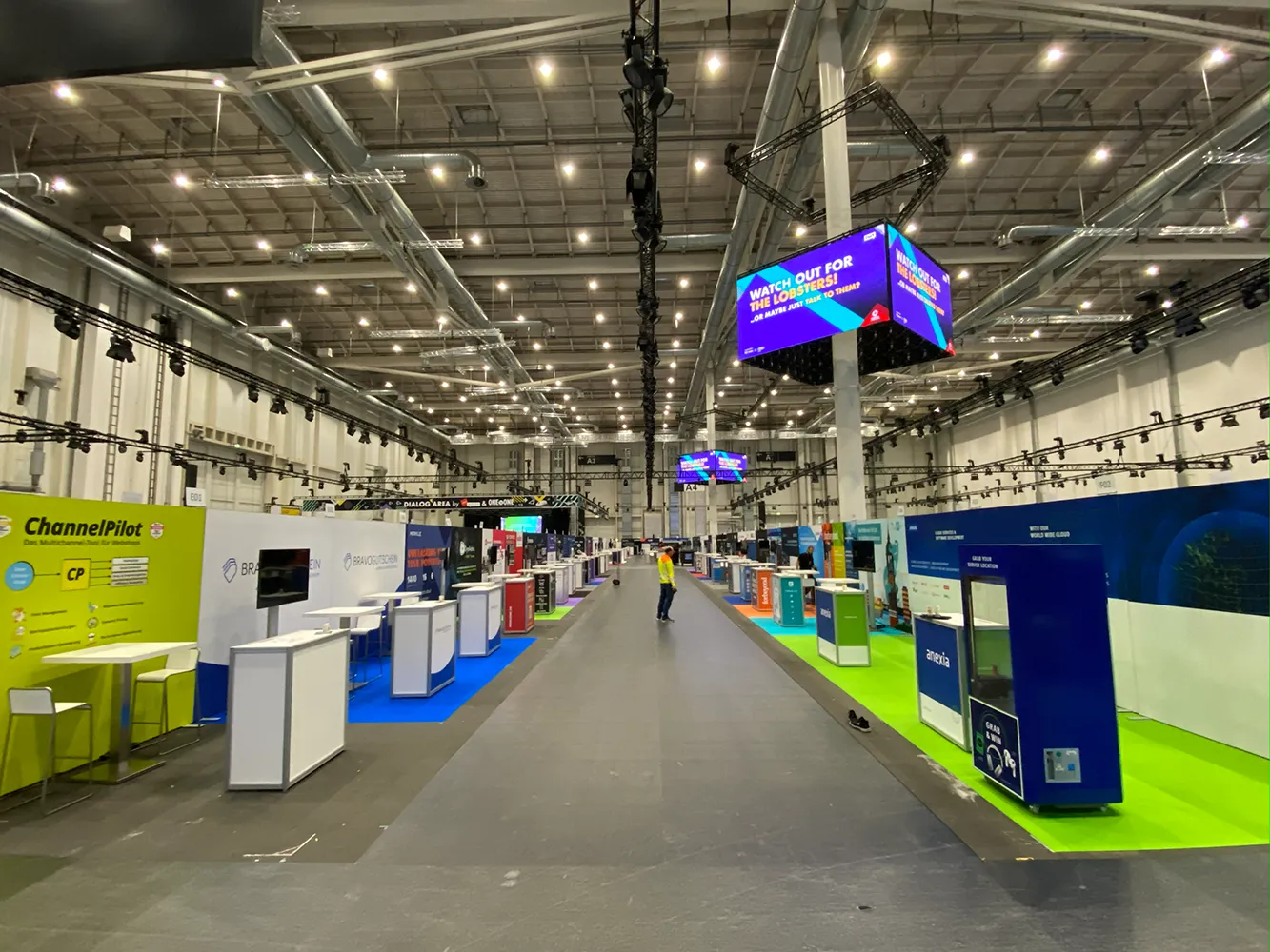 Messeteppich in einer großen Messehalle auf der OMR Hamburg mit aufgebauten Messeständen und farbigen Bodenflächen.