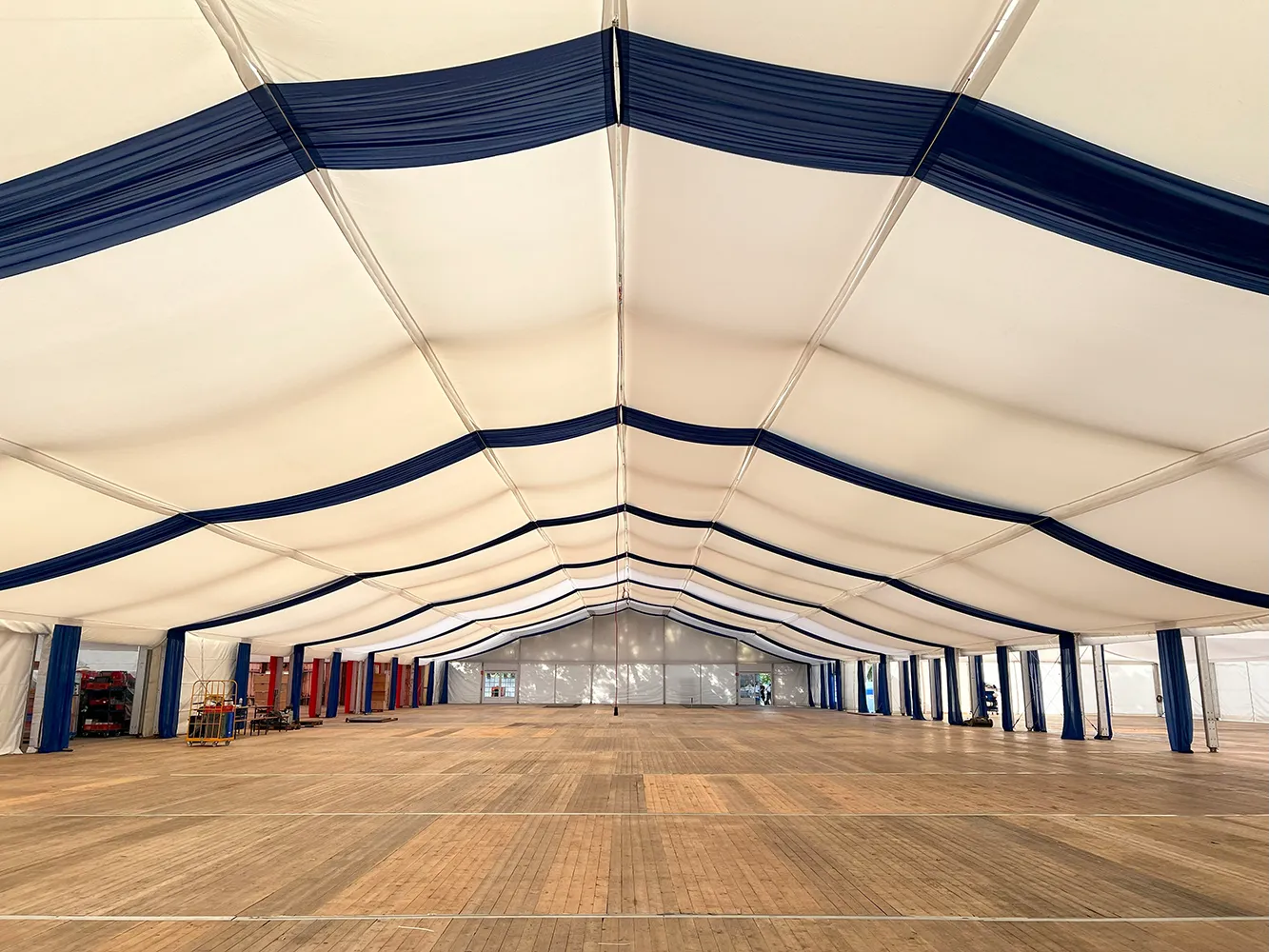 Zelthimmel in Weiß und Dunkelblau im großen Festzelt – elegante Oktoberfestdekoration mit Holzfußboden.
