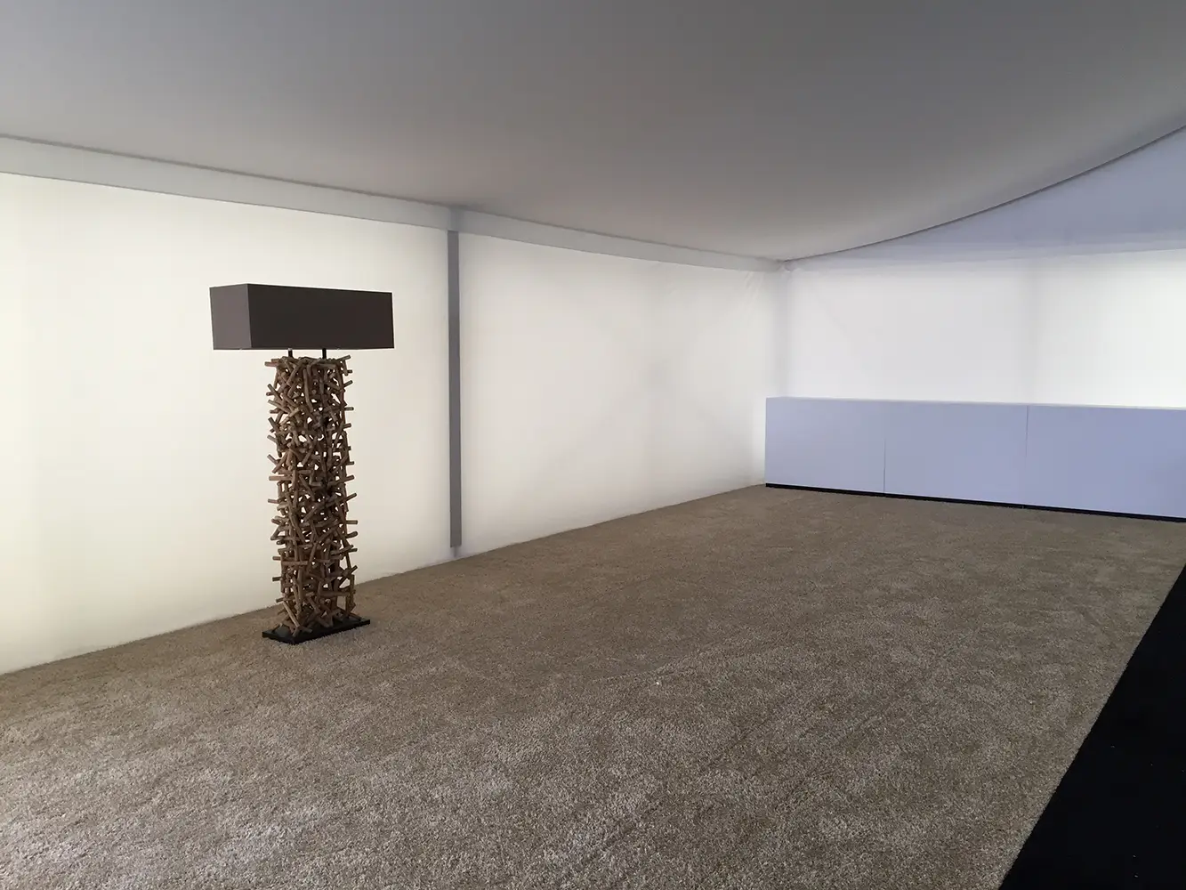 Loungebereich mit weißem Zelthimmel, glatter Seitenverkleidung und beigem Messeteppich – stilvolles Raumdesign von Skydeko.