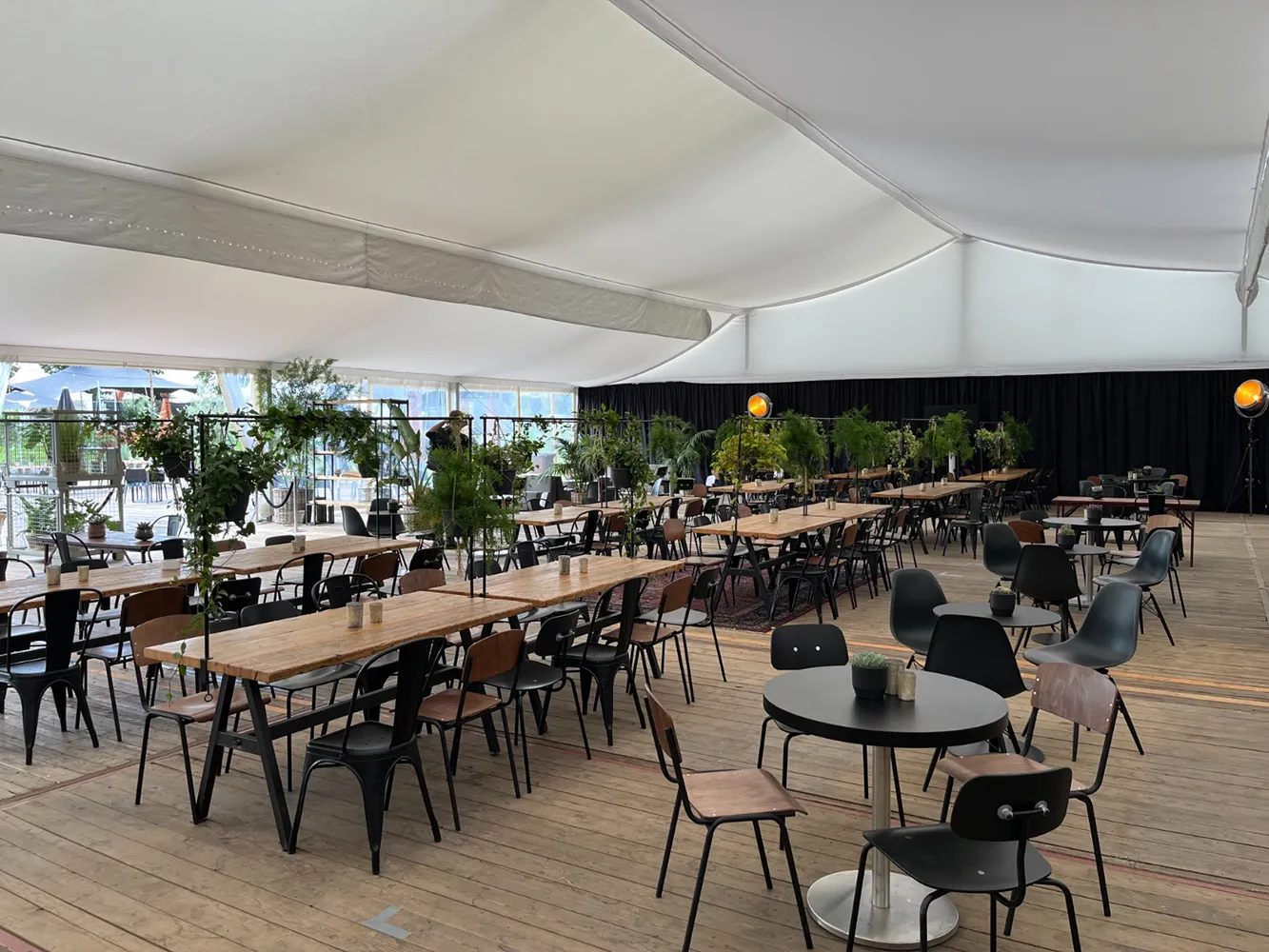 Eventzelt mit weißem Zelthimmel, Holzboden und moderner Möblierung – Festivalbereich mit Pflanzen und Lounge-Atmosphäre von Skydeko.