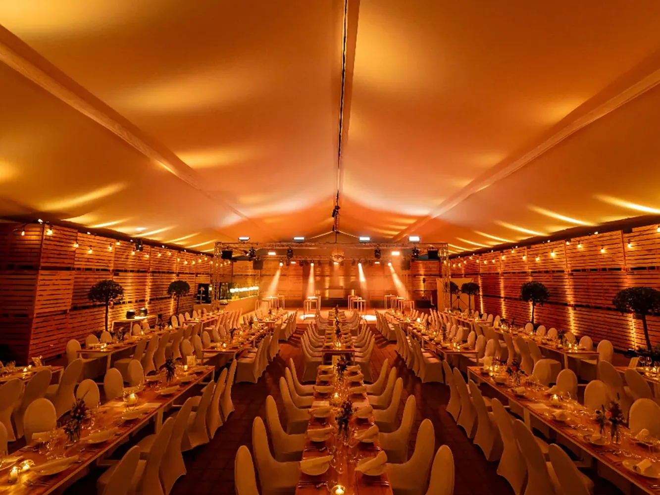 Hallenverkleidung mit weißem Zelthimmel und Lichtdesign für elegante Hochzeitsdekoration in einer Industriehalle.