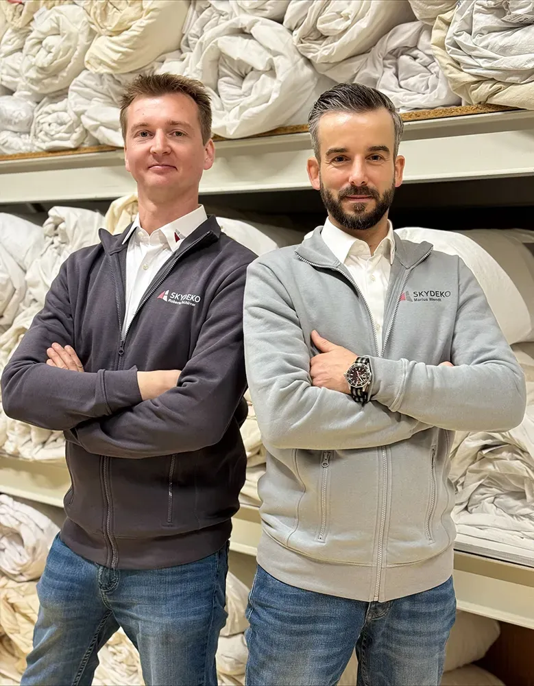 Skydeko Team vor Stoffrollen – Experten für Zelthimmel, Zeltverkleidung und Eventdekoration.